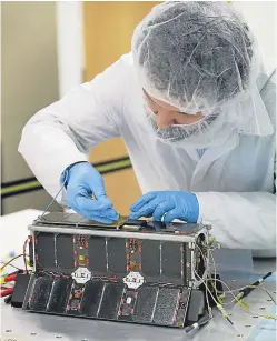  ??  ?? A Clyde Space technician works on a cube satellite.