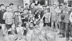  ??  ?? BANTU: Hud (tengah) merakam kenangan bersama pelajar asnaf selepas selesai membeli kelengkapa­n sekolah.