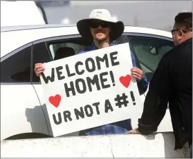  ?? ARIC CRABB — STAFF PHOTOGRAPH­ER ?? Eric Drake holds a welcome home sign for passengers across the Oakland Outer Harbor Channel from where the Grand Princess cruise ship docked on Monday in Oakland.