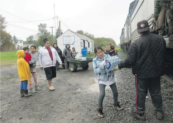  ?? PHOTOS: SELENA ROSS / FINANCIAL POST ?? Families in Thicket Portage unload supplies from a train on the Hudson Bay Railway in September. In the summer, the train is the only land transport in or out of the community.