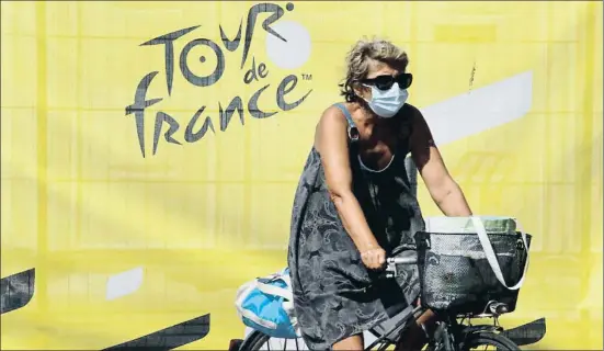  ?? CHRISTOPHE ENA / AP ?? Una mujer circula en bicicleta en Niza, ante uno de los carteles anunciador­es de la presencia del Tour de Francia