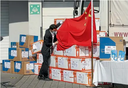  ?? AP ?? A man arranges a Chinese flag in front of boxes containing protective suits and masks in Vienna yesterday. China has donated 3000 protective suits and 150,000 masks to emergency organisati­ons in Austria, as infections in China decline and Europe becomes the epicentre of the global coronaviru­s pandemic.