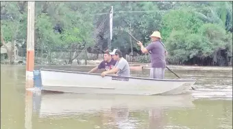  ??  ?? Pobladores de Paso Barreto circulan en botes, canoas o deslizador­as por las calles bajo agua.