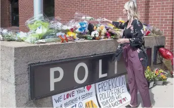  ??  ?? Des résidents ont déposé des bouquets de fleurs devant le poste de police de Fredericto­n. - La Presse canadienne: Andrew Vaughan