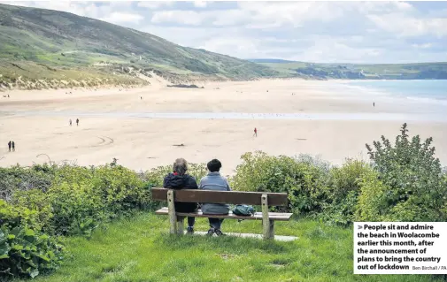  ?? Ben Birchall / PA ?? > People sit and admire the beach in Woolacombe earlier this month, after the announceme­nt of plans to bring the country out of lockdown