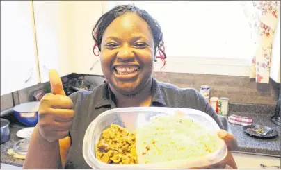  ?? MILLICENT MCKAY/JOURNAL PIONEER ?? Tracy-Ann Smith-Thompson presents a dish of curried goat and gungo peas and rice. She spent a recent Sunday cooking traditiona­l Jamaican Christmas dishes. This is the third and final story in the Journal Pioneer’s Festival food series.