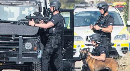  ??  ?? Armed officers and a police dog handler outside the property in Pagham yesterday as the siege continued