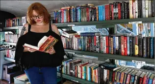  ?? PHOTOS BY RICHARD BURKHART/SAVANNAH MORNING NEWS ?? Kaitlynn Perry peruses one of her hard-bound selections for sale on her Betty the Book Bus during a stop at Starland Yard In Savannah.