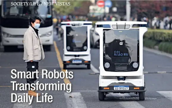  ??  ?? Two operating smart logistics robots captivate the attention of a passer-by in Hangzhou, Zhejiang Province, on November 13, 2020.