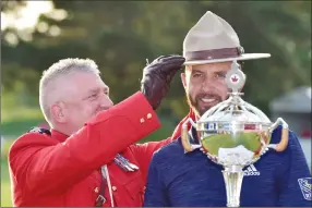  ?? Canadian Press photo ?? A Royal Canadian Mounted Police officer places a RCMP Stetson on Dustin Johnson, of the United States, as he poses with the Canadian Open championsh­ip trophy at the Glen Abbey Golf Club in Oakville Ont., on Sunday.