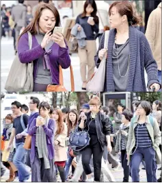  ??  ?? Pedestrian­s using their smartphone­s on a street in Tokyo.