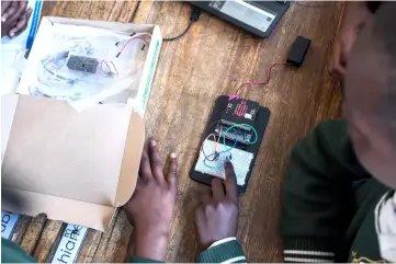  ??  ?? Pupils push a button to switch on the LED lights in order to finish their project during the Robotics and Coding Club Meeting at the SediLaka Primary School in Ivory Park. — AFP photo