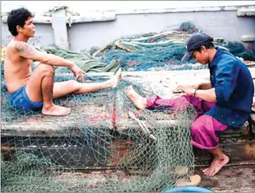  ?? NICOLAS ASFOURI/AFP ?? A migrant worker repairs a net on a fishing boat in Thailand’s Rayong province.