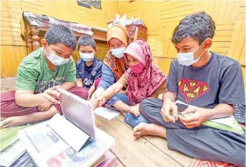  ??  ?? TABLET FOR STUDYING: Siti Nur Bariah Sidek, 15, (centre) and her siblings using a tablet contribute­d by Malaysia Crime Prevention Foundation executive council member Kelvin Yeap for studying and learning at home at Kampung Sri Kulim Melor in Kota Bharu. The five siblings have to share their mother’s cellphone to study online. -Bernama photo