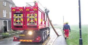  ?? Richard Williams ?? > The clean-up in Beaumaris after Saturday’s flood. The fire service on the seafront pumps water