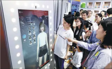  ?? ZHU XINGXIN / CHINA DAILY ?? Visitors experience smart fitting at Alibaba’s booth at an exhibition in Fuzhou, Fujian province, in April.