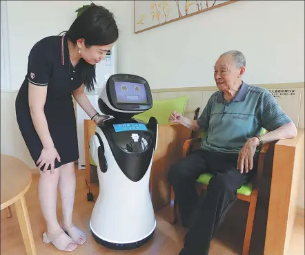  ?? LIU XU / FOR CHINA DAILY ?? A social worker (left) guides a senior citizen on how to interact with an artificial intelligen­ce-powered robot at a community center in Zhengzhou, Henan province.