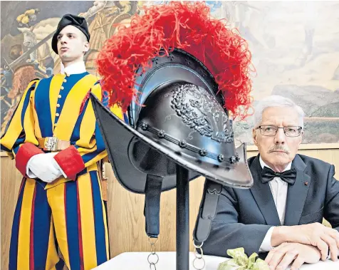  ??  ?? A Swiss Guard stands by as Peter Portmann, the Black Helmets project director, presents the 3D-printed helmet bearing the coat of arms of Pope Julius II at the Vatican