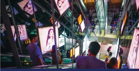  ?? ?? Adverts are reflected in mirrors on an escalator in Admiralty. Photo: Xiaomei Chen