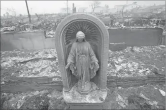  ?? Shannon Stapleton/reuters ?? A statue is seen among homes devastated by hurricane Sandy in the Queens borough of New York on Tuesday. Millions of people across the eastern U.S. awoke to similar scenes of destructio­n.