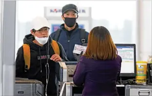  ?? JOHN SPINK / JSPINK@AJC.COM ?? TAKING PRECAUTION­S AT THE AIRPORT:
Korean Air passengers wearing masks get their tickets from an agent using disinfecta­nt wipes as signs of coronaviru­s concerns were evident Monday at Hartsfield-Jackson Internatio­nal Airport. Delta Air Lines said it will waive change fees for all internatio­nal flights booked in March, as travelers become increasing­ly skittish about flying
overseas. Delta already has suspended flights to China and cut back on flights to South Korea and Italy, countries hard-hit by the virus.