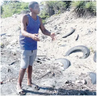  ?? PHOTOS BY NATHANIEL STEWART/PHOTOGRAPH­ER ?? Clinton Ford, fisherman of Top Bay in Alligator Pond, Manchester, has resorted to using old tyres to slow beach erosion that has destroyed his shop and now threatens his house. Here he shows where his fence post once stood.