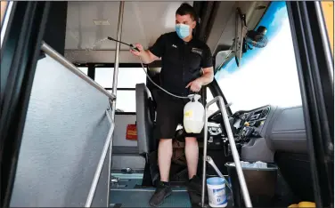  ?? (AP/Charlie Neibergall) ?? Des Moines Public Schools mechanic Kelly Silver disinfects a school bus Wednesday in Iowa. Public schools around the country are preparing to reopen for at least some in-class instructio­n. More photos at arkansason­line.com/730covid/.