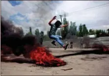  ??  ?? A Kashmiri Muslim protester jumps over a burning tire set up as a road block during a protest Tuesday in Srinagar, India.