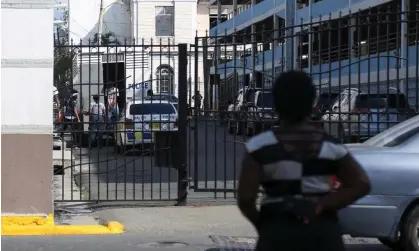  ?? Photograph: Gilbert Bellamy/Reuters ?? A woman watches as alleged gang members step out of a police truck after arriving at court, in Kingston, Jamaica, in January 2022.