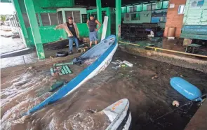  ?? INTI OCON/AP ?? Fishermen survey partially submerged boats in Bluefields, Nicaragua, Sunday after Hurricane Julia swept through. By Monday, Julia had moved inland over Guatemala as a tropical depression.