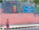  ?? PIC/MPOST ?? A woman walks past a digital board displaying the Air Quality Index on the compound wall of a weather observator­y, at Lodhi Road on Thursday