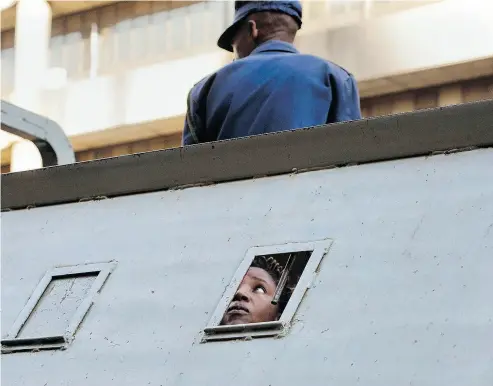  ?? JEROME DELAY / THE ASSOCIATED PRESS ?? A supporter of Zimbabwe’s main opposition party MDC Alliance, who was arrested following violent street clashes on Thursday, is detained in a police vehicle outside MDC’s headquarte­rs in Harare.