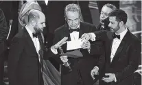  ??  ?? “La La Land” producer Jordan Horowitz, left, presenter Warren Beatty, center, and host Jimmy Kimmel right, look at an envelope announcing “Moonlight” as best picture at the Oscars on Sunday,