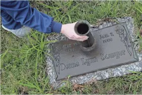  ?? DAN ANDERSON/AP ?? Amber Sawyer adjusts the vase on her sister Donna’s grave in Pascagoula. The Jehovah’s Witness community in which they grew up shunned Donna weeks before she shot herself. Amber was shunned, too.
