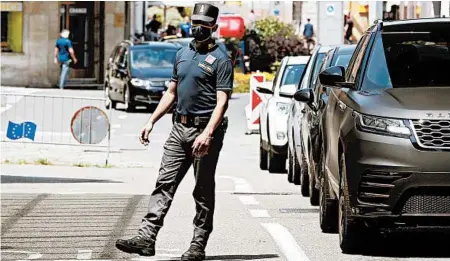  ?? ANTONIO CALANNI/AP ?? A border police officer wears a mask to prevent the spread of the virus Wednesday as cars cross into Italy at the Italian-Swiss border in Ponte Chiasso.