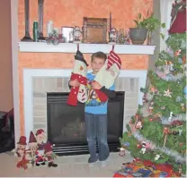  ??  ?? LEFT: Kathie Devlin’s son hangs stockings on the mantel in preparatio­n for St. Nick.