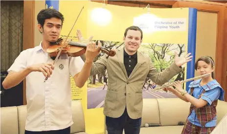  ??  ?? Young musicians big and small, from all walks of life, unite to form the Orchestra of the Filipino Youth (top). Music director Joshua Dos Santos is flanked by concertmas­ter JM Eserjose and flutist Carmela Casas (above).