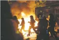  ?? MARKUS SCHREIBER THE ASSOCIATED PRESS ?? Police officers are silhouette­d by fires lit by demonstrat­ors Thursday during a protest against the G-20 summit in Hamburg, Germany.