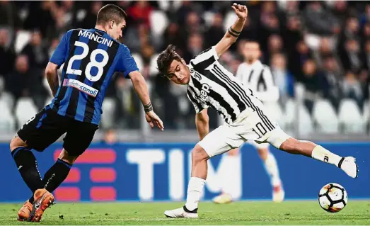  ?? — AFP ?? Dangerous: Juventus’ Paulo Dybala (right) trying to dribble past Atalanta’s Gianluca Mancini during the Serie A match at the Allianz Stadium on March 14.