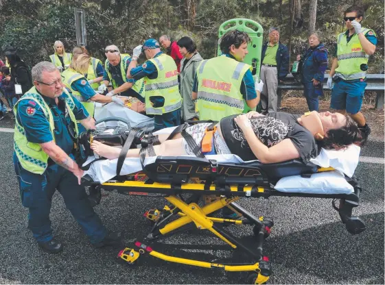  ?? Picture: GLENN HAMPSON ?? Queensland Ambulance crew treat people injured in the collision; and (below) Japanese tourists who were on the bus.