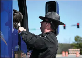  ?? (Arkansas Democrat-Gazette/Stephen Swofford) ?? Officer Kreston Taylor, with the Arkansas Highway Police, pets a dog in the passenger seat of a truck Saturday as he directs the driver at the shutdown stretch of Interstate 430.