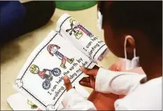  ?? Don Campbell / Associated Press ?? Students read an Earth Day coloring book in Claire Martin's kindergart­en class as part of Earth Day activities on Friday at the Discovery Enrichment Center in Benton Harbor, Mich.