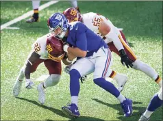  ?? John Minchillo / Associated Press ?? Washington’s Deshazor Everett (22) and Cole Holcomb (55) tackle Giants quarterbac­k Daniel Jones during the second half on Oct. 18 in East Rutherford, N.J.