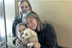  ?? JESSICA HARTMAN/THE ASSOCIATED PRESS ?? Monica Newhard, right, and her granddaugh­ter, Helen Welch, hold their pet bichon frise, Zoey, as the dog’s rescuer, Christina Hartman, stands behind them.