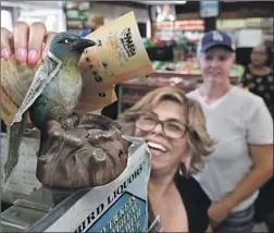  ?? Mel Melcon Los Angeles Times ?? TESTING L.A. folklore, Sydney Morua of Marina del Rey rubs lottery tickets on Bluebird Liquor’s figurine Friday in hopes of getting some good luck.