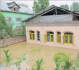  ?? ■ WASEEM ANDRABI/HT ?? Residents keep tabs on the rising water level outside their house in Kursoo Rajbagh area of Srinagar. As the rains continued to lash the Valley, the government has sounded an alert in many lowlying areas.