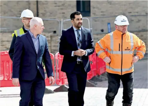  ?? Reuters ?? Scotland’s First Minister Humza Yousaf and SNP MSP Joe Fitzpatric­k walk with site worker Ken Macpherson, as they visit a housing developmen­t in Dundee, Scotland, Britain.