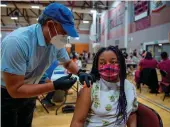 ?? Tribune News Service/the Sacramento Bee ?? Lauren Burks, 13, gets her first dose of the Pfizerbion­tech COVID-19 vaccine in May at Natomas High School in Sacramento.