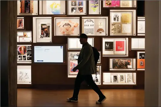  ?? (AP/Sue Ogrocki) ?? A man walks past a portion of the archive wall Thursday at the Bob Dylan Center in Tulsa, Okla.