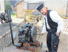  ?? FOTO: JANA MACK ?? Mit Hilfe einer Zündlunte startet Herbert Ott seinen Standmotor. Durch die Drehung des Motors entzündet sich die Lunte und über Flachrieme­n betreibt der laufende Motor verschiede­nste Gerätschaf­ten, hier eine Schrotmasc­hine.